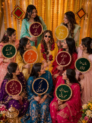bride and bridesmaids holding mehndi props and dholki props for wedding photoshoot decoration