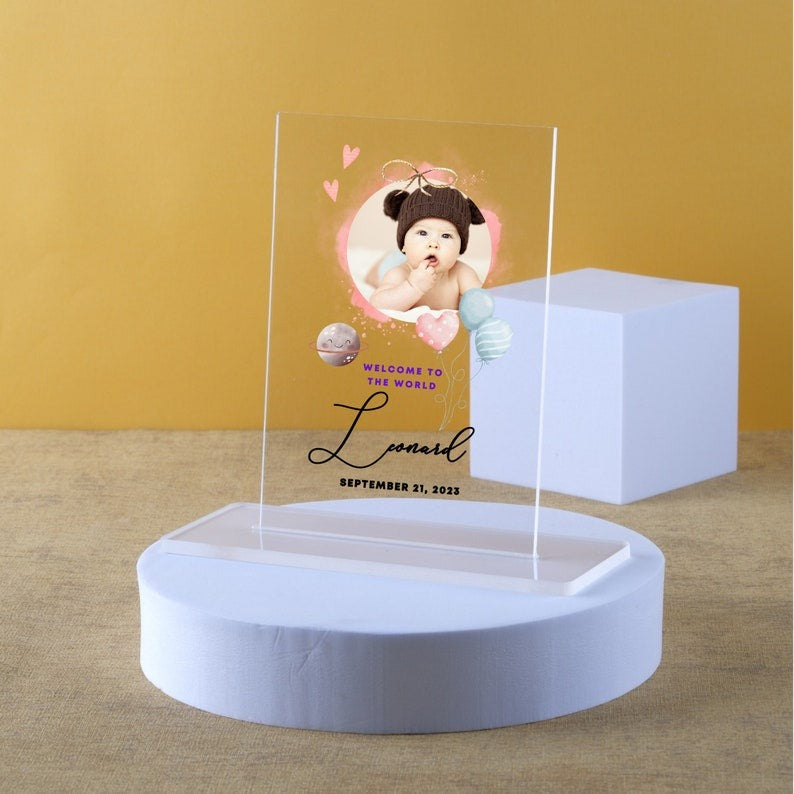 Custom baby photo acrylic plaque with Leonard’s newborn welcome sign, featuring a baby portrait and birth date, displayed on a stand
