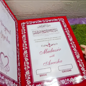Open customized velvet Nikkah Nama certificate with "Mudassir & Areesha" text, featuring a couple illustration and Islamic calligraphy in a red velvet cover, held against a green backdrop