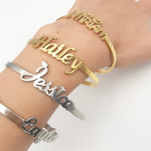 Engraved cuff bangle bracelets in gold and silver with the names "Miriam," "Haley," "Jessica," and "Layla," worn on a wrist