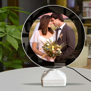 LED magic mirror photo frame with a wedding photo of a bride and groom, displayed on a table with plants in the background