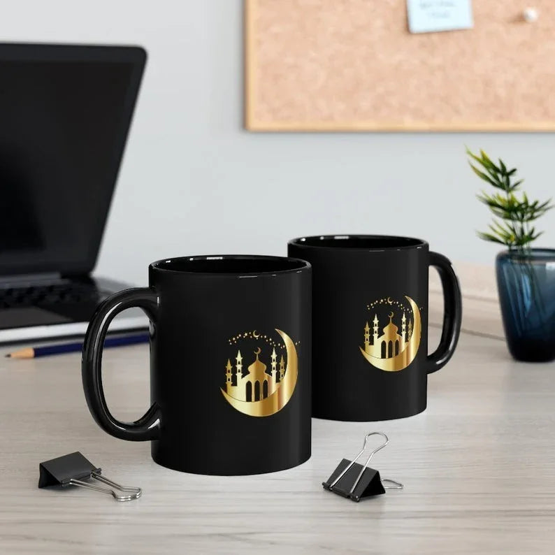 Pair of Ramadan Moon and Mosque Mugs with a golden crescent moon and mosque silhouette design, placed on a desk with office accessories.