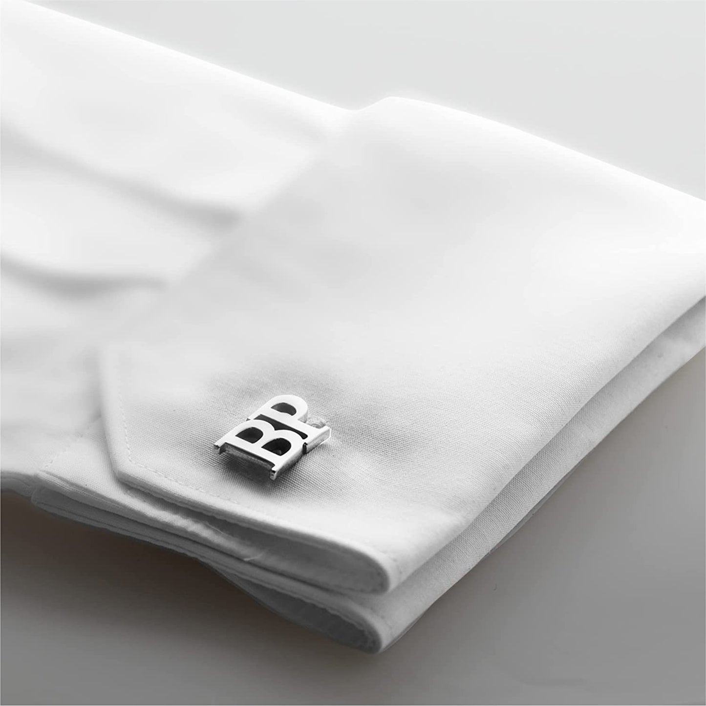 Personalized silver cufflinks with "BR" initials, displayed on a white shirt cuff with a navy blue suit