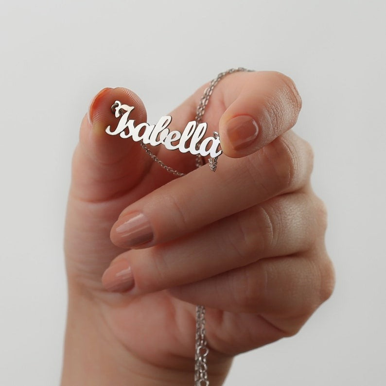 Personalized jewelry name necklace in silver with the name "Isabella," held in hand with a white background