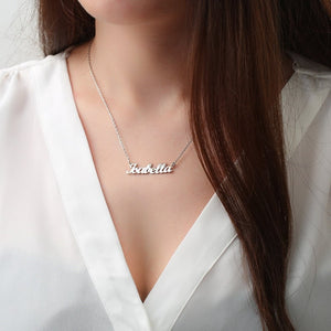 Personalized jewelry name necklace in silver with the name "Isabella," worn on a white shirt with long brown hair visible