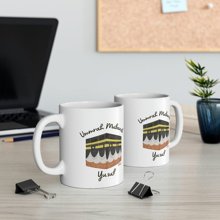 Personalized Umrah Mubarak mugs featuring the Kaaba design with the name "Yusuf" and the year "2023", perfect for commemorating the sacred Umrah journey.