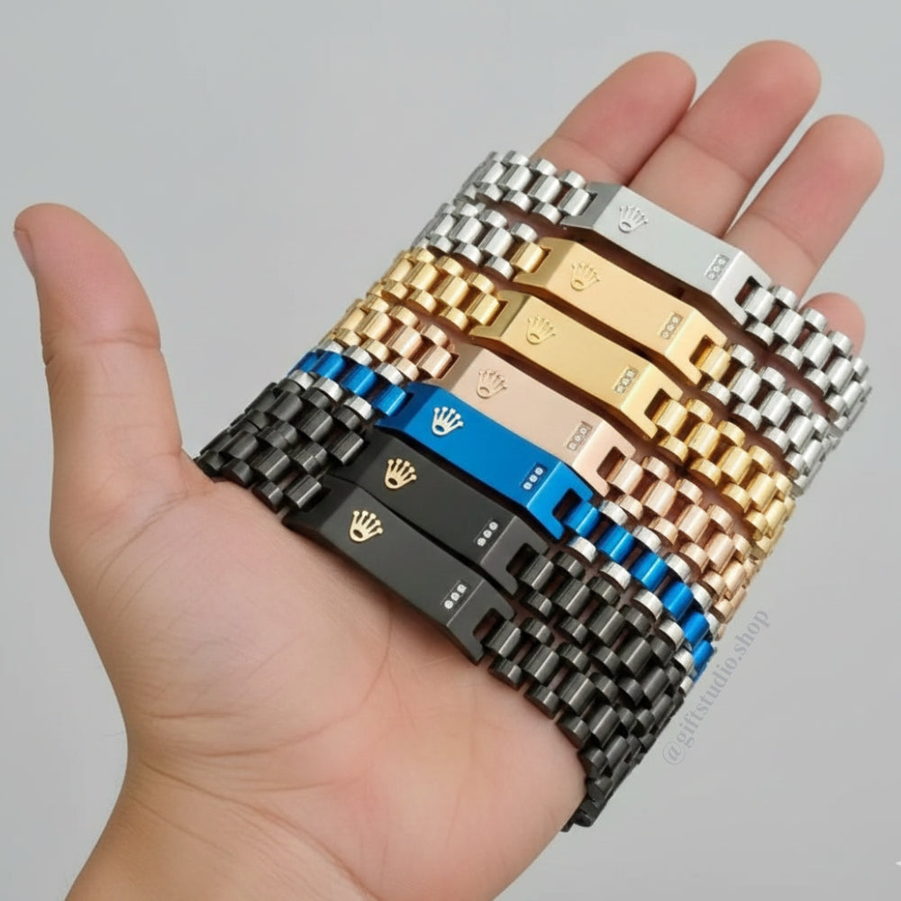 A hand holding multiple Rolex-style stainless steel bracelets in black, blue, gold, rose gold, and silver colors, featuring luxury clasp design by Gift Studio.