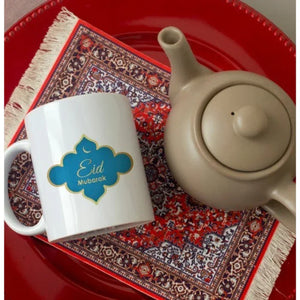 Close-up of Eid Mubarak Mug featuring a vibrant blue and gold design, placed on a red tray with a teapot.