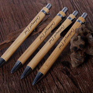 Set of five customized bamboo wood ballpoint pens with engraved text, featuring a retractable medium-point design for smooth writing