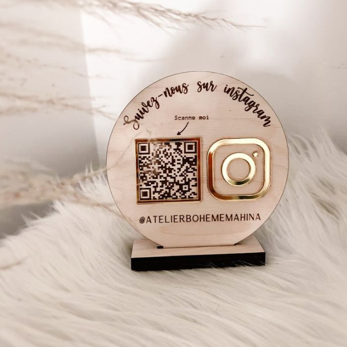 Custom wooden social media sign with a QR code and gold acrylic Instagram logo, featuring the handle ,displayed on a black base with a soft background.