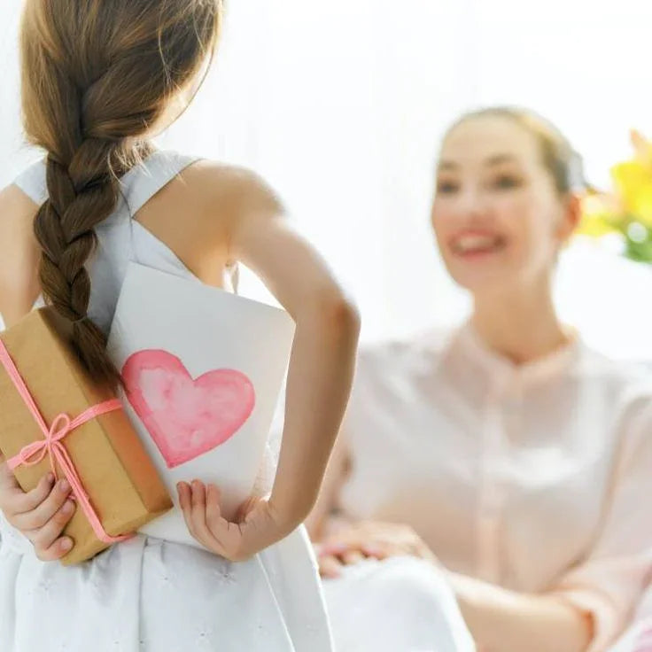 Little girl holding gift box and heart drawing for mom, perfect for customized gifts and special occasions