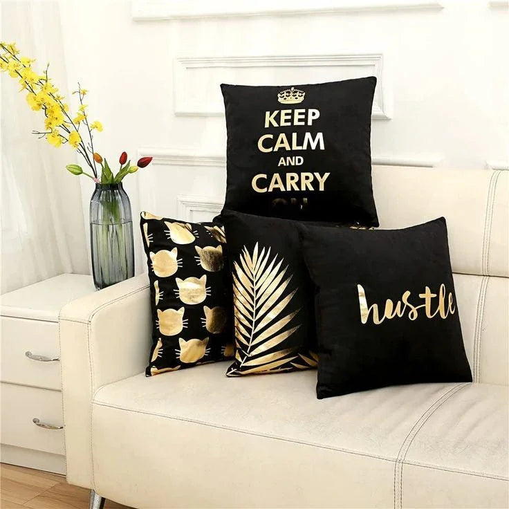 Black and gold decorative throw pillows with 'Keep Calm', cat, leaf, and 'hustle' designs on sofa