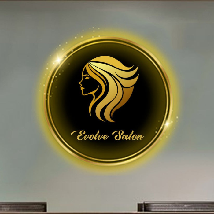 Custom beauty salon neon sign with "Evolve Salon" text and glowing silhouette, mounted on a wall above a wooden reception desk in a modern salon


