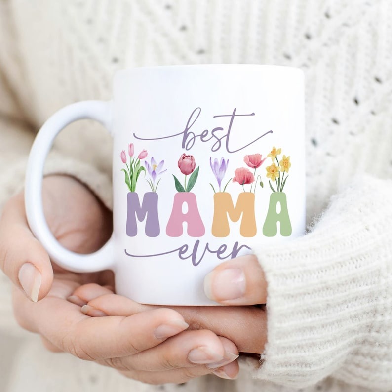 Best Mama Ever mug with vintage floral wildflower design, held by hands in a cozy sweater