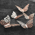 Elegant butterfly wall decor in rose gold metal, 3D butterfly wall art with delicate floral cut design on dark textured background.