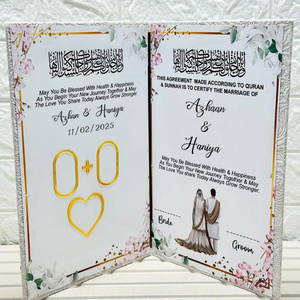 Custom Nikkah Nama velvet booklet open, displaying "Azhaan & Haniya" with date "11/02/2025," featuring floral designs and Islamic wedding blessings against a white brick wall