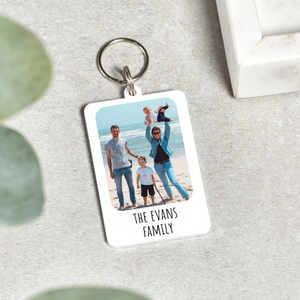 A personalized family photo keychain featuring an image of a smiling family at the beach with the text "The Evans Family" engraved below.