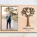 Custom engraved wooden photo frame with a laser-cut tree and heart design, personalized with the names 'Samantha & Rafael' and their engagement date, holding a 4x6 photo of the couple celebrating."