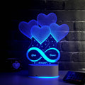Eternal Love 3D LED night light with heart-shaped balloons and infinity design, displayed on a bedroom table with a mug