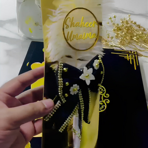 Open customized Nikah velvet book kit with "Shaheer & Umaima" text, featuring Islamic calligraphy, floral designs, and a bride and groom illustration, held by a hand