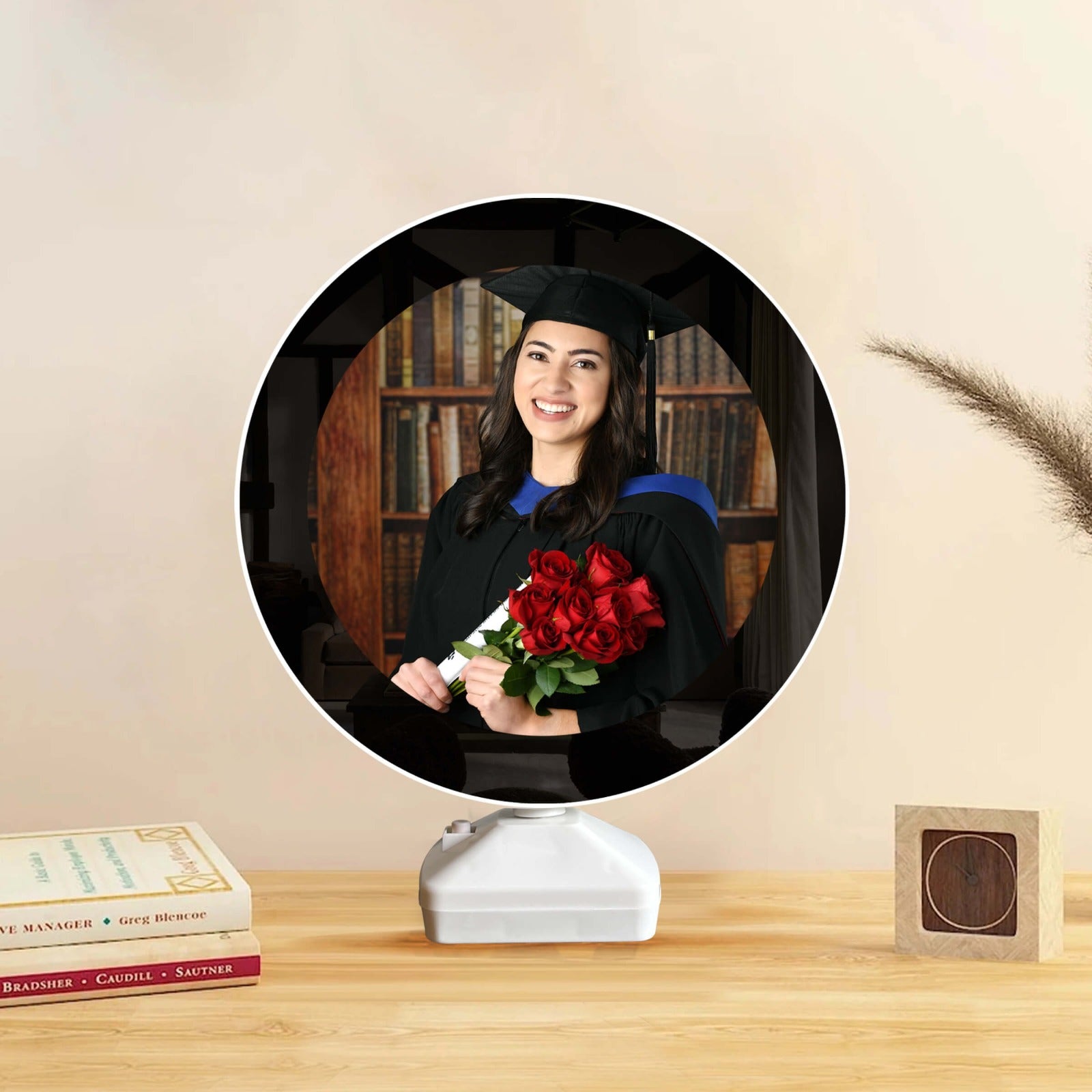 LED magic mirror photo frame with a graduate holding red roses, displayed on a wooden table with books and decor