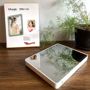 LED magic mirror photo frame in mirror mode with packaging box, displayed on a wooden table with a plant