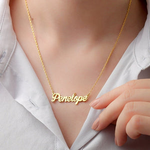 Personalized jewelry name necklace in gold with the name "Penelope," worn on a white shirt, held by hand