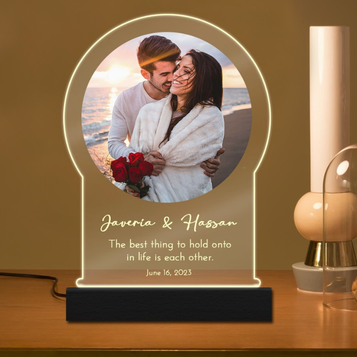 Personalized couple night light with photo of Javeria & Hassan, glowing with a soft LED light, engraved with a romantic message, placed on a wooden table