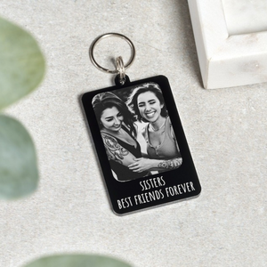 A black-and-white custom photo keychain with the text "Sisters Best Friends Forever," featuring two smiling women embracing.