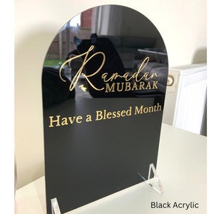Ramadan Mubarak Acrylic Sign in black with gold Arabic calligraphy and the message "Have a Blessed Month.