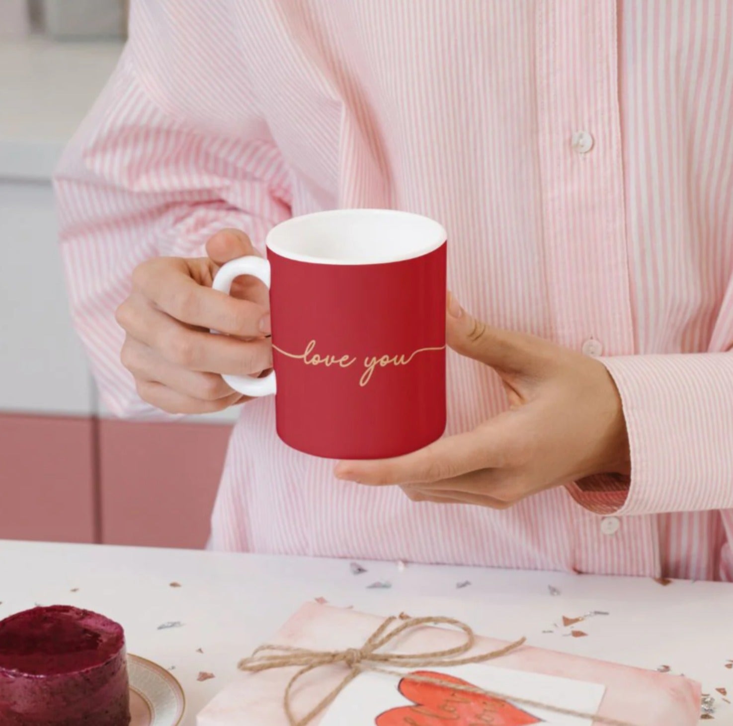 Person holding a red ceramic mug with 'love you' written in gold script, perfect for gifting."
