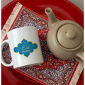  Close-up of Eid Mubarak Mug featuring a vibrant blue and gold design, placed on a red tray with a teapot.