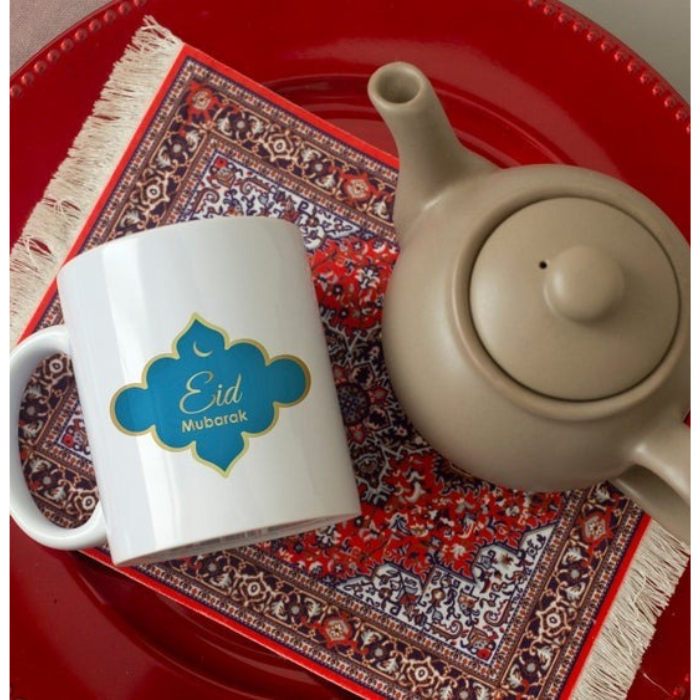  Close-up of Eid Mubarak Mug featuring a vibrant blue and gold design, placed on a red tray with a teapot.