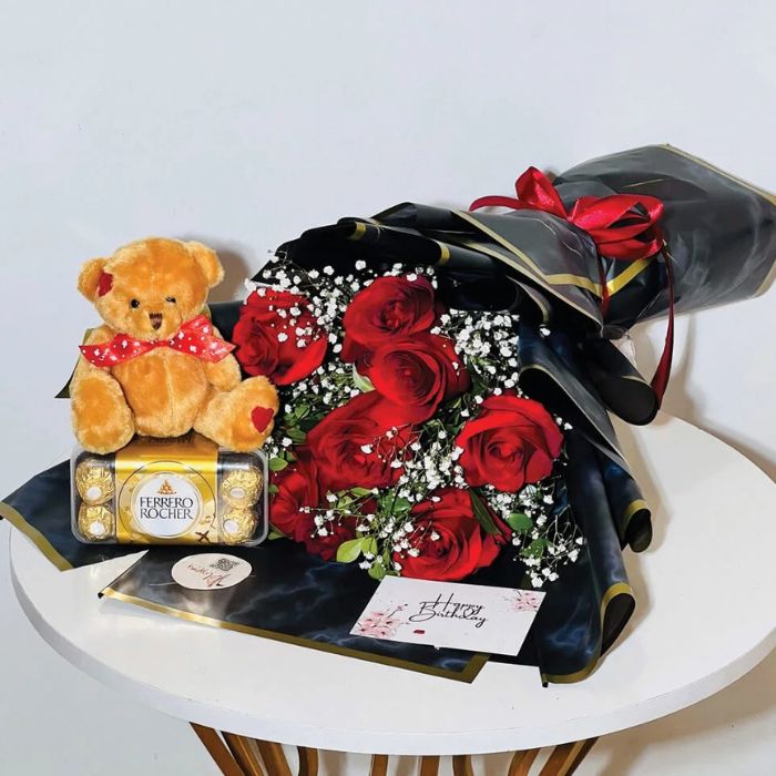 Birthday gift set with red roses, teddy bear, and Ferrero Rocher chocolates in elegant wrapping.