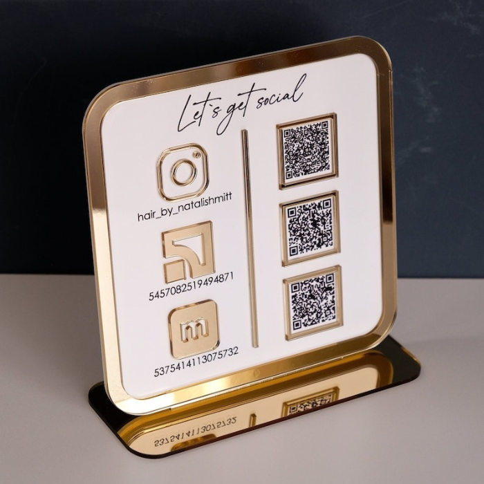 Freestanding acrylic business sign with QR codes for social media and Wi Fi access, placed on a modern reception counter.