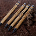 Set of five customized bamboo wood ballpoint pens with engraved text, featuring a retractable medium-point design for smooth writing