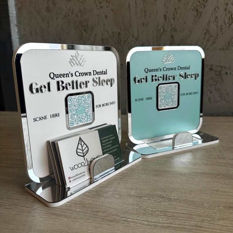  A professional Queen’s Crown Dental QR Code Display in white and light blue, featuring a business card holder for easy access to digital services.