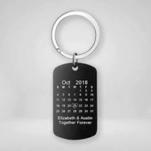 Custom engraved black metal keychain featuring a calendar design with a highlighted date and a personalized message.