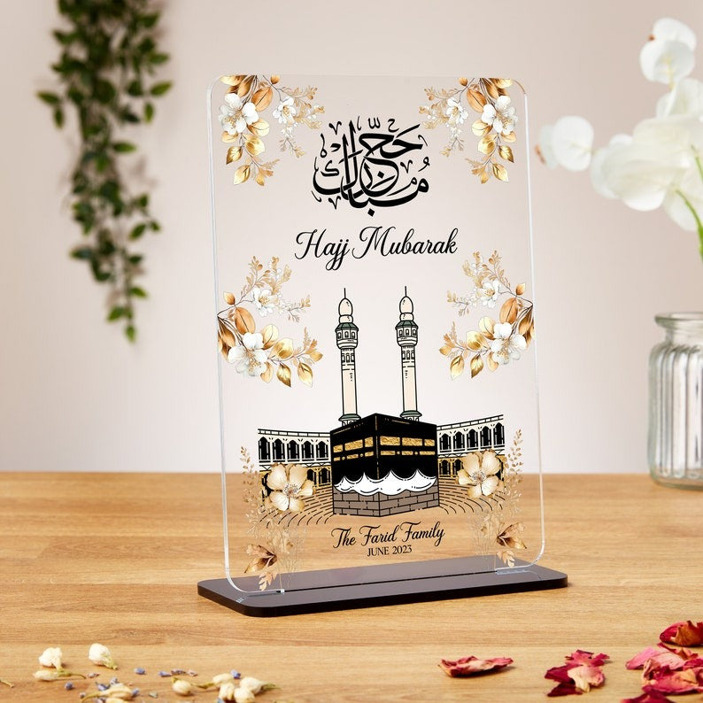A premium Hajj Mubarak acrylic plaque with a Kaaba design, floral accents, and Arabic calligraphy, personalized with names and dates. Ideal for Hajj, Umrah, Eid, Nikkah, and Ramadan gifts.