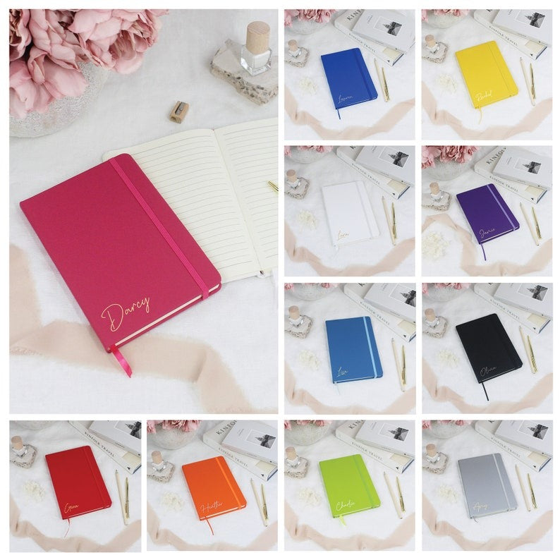  Set of three personalized notebooks in black, blue, and pink, featuring custom name engravings.