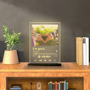 Spotify music night lamp with photo of couple making a heart, displaying "I’m Yours by Jason Mraz" with Spotify code, on a wooden table with books and a plant